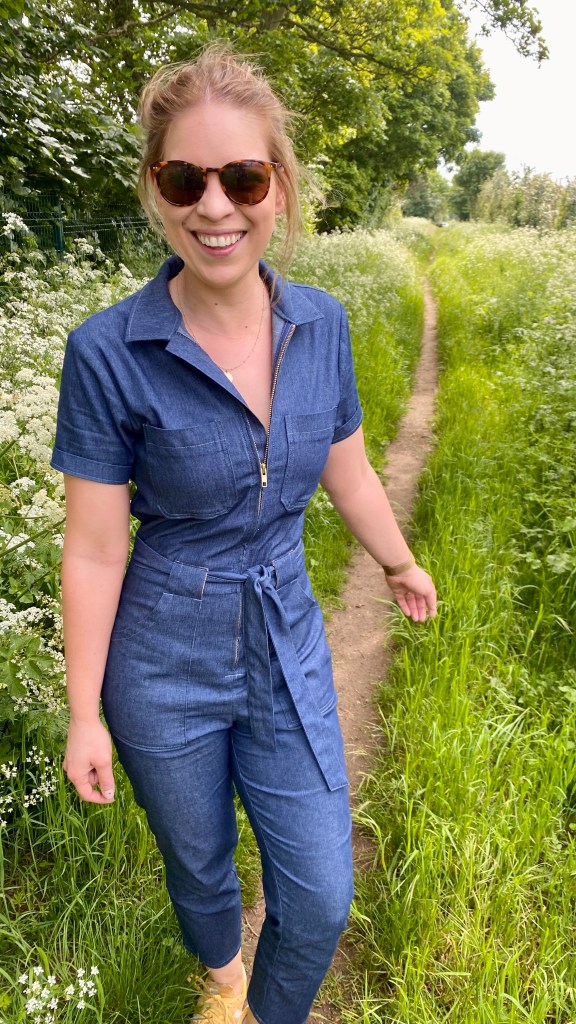 Full length photo of Jen Rich wearing a blue denim jump suit.